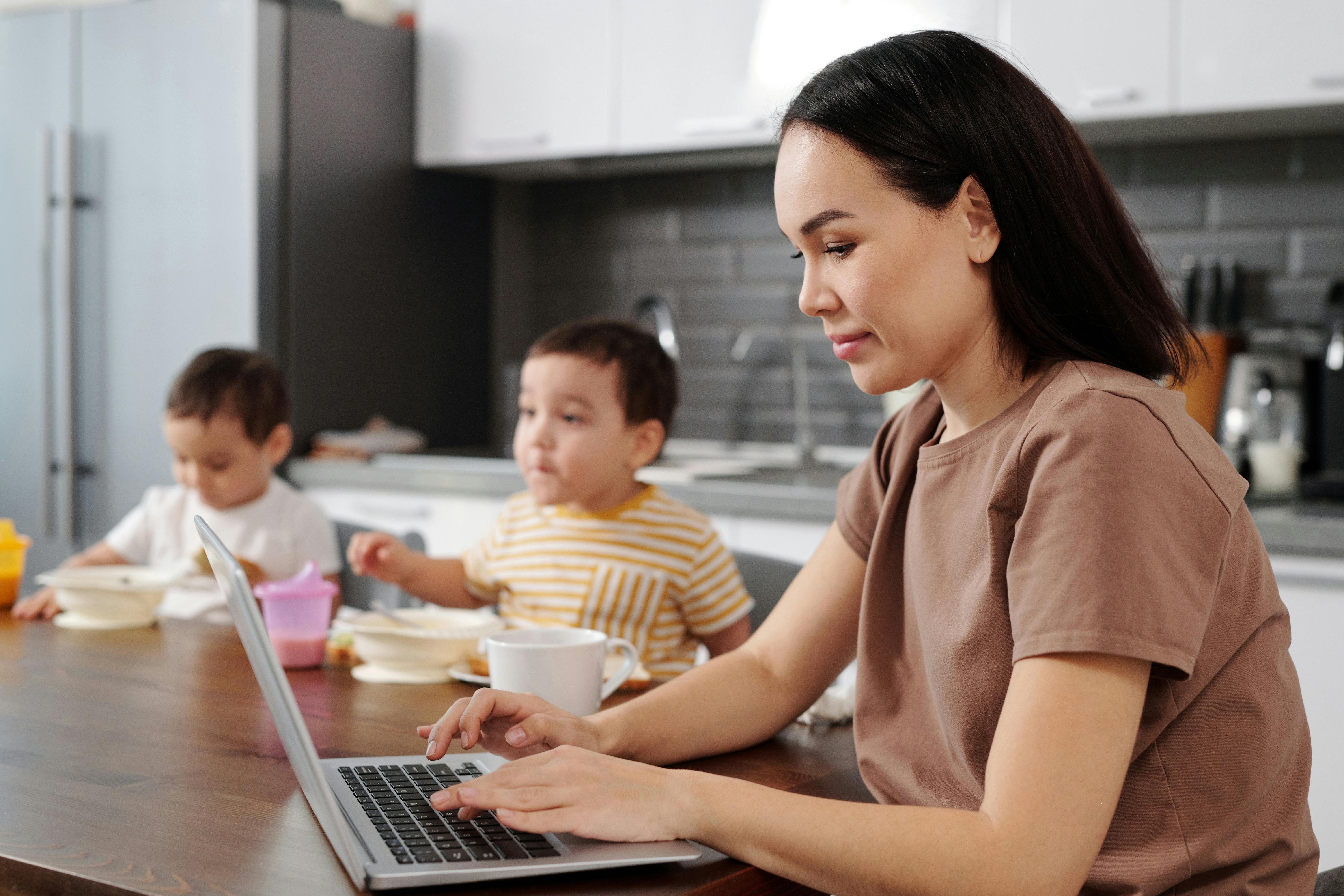 a woman working on a laptop with children in the background