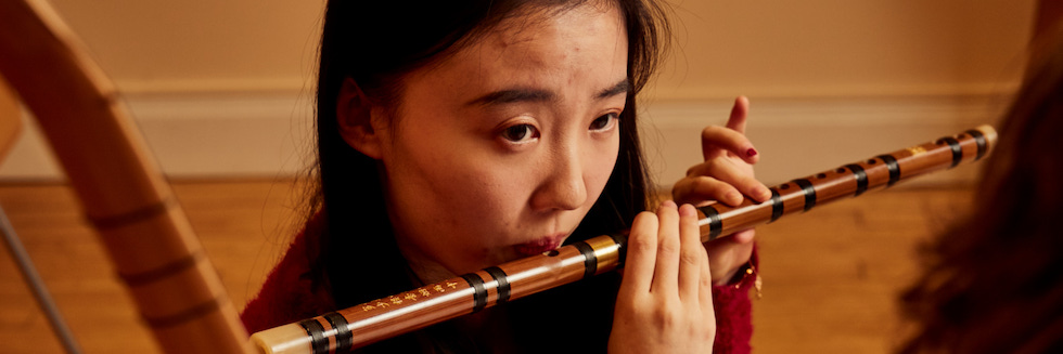 Woman playing a wooden flute.