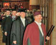 A University Ceremonial Officer (Professor Dick Clements) leads one of the stage parties from the Great Hall at the end of the degree congregation.