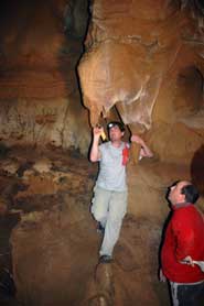 Spanish Archaeologist Javier Alcolea with Alistair Pike balanced precariously to sample a stalactite painted with a small anthropomorph in Tito Bustillo cave, Asturias. The deliberate placing of the paintings in difficult to reach places was quite common. This chamber was in a very remote part of the cave, requiring a climb and a descent to reach. Painting the stalactite would have been at least a