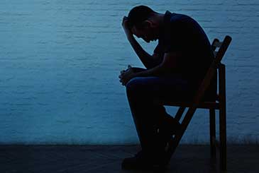 Silhouette of man holding head in hands
