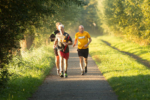 A group of older men jogging along a path