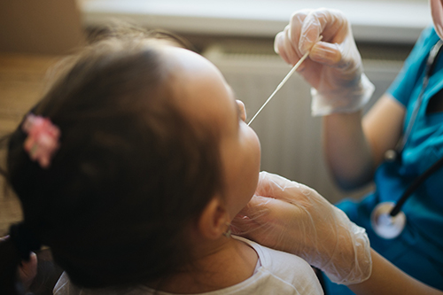 Doctor holding a swab for a mucus sample from a child's nose or mouth