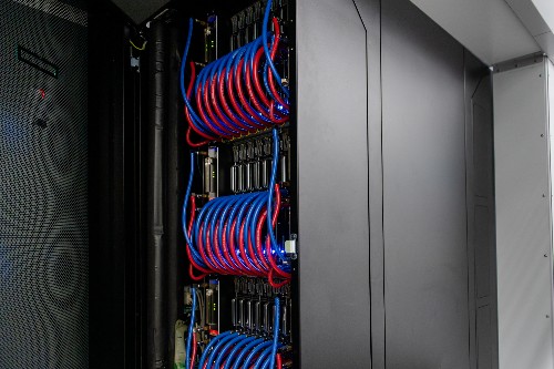 Blue and red cables curving in neat rows to one side of a dark cabinet.
