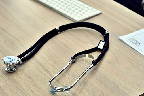 A stethoscope on a desk by a computer keyboard