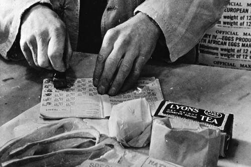 Civilian rationing: A shopkeeper cancels the coupons in a woman's ration book in 1943.