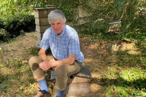 Botanic Garden curator Nick Wray sitting beside bee hives in Bristol