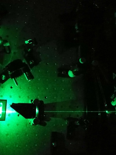 Ultrafast laser - green laser on a black board pointing through a glass