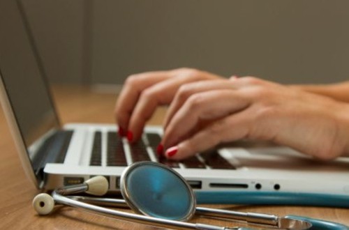person at a laptop with stethoscopoe