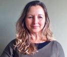 A woman with long curly blond hair wearing a brown jumper