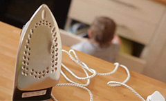 Iron on a surface, with child in the background