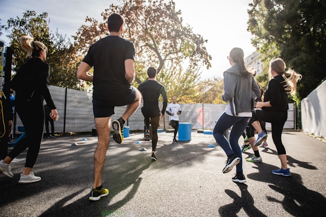 Family doing fitness exercises together outdoors with instructor.