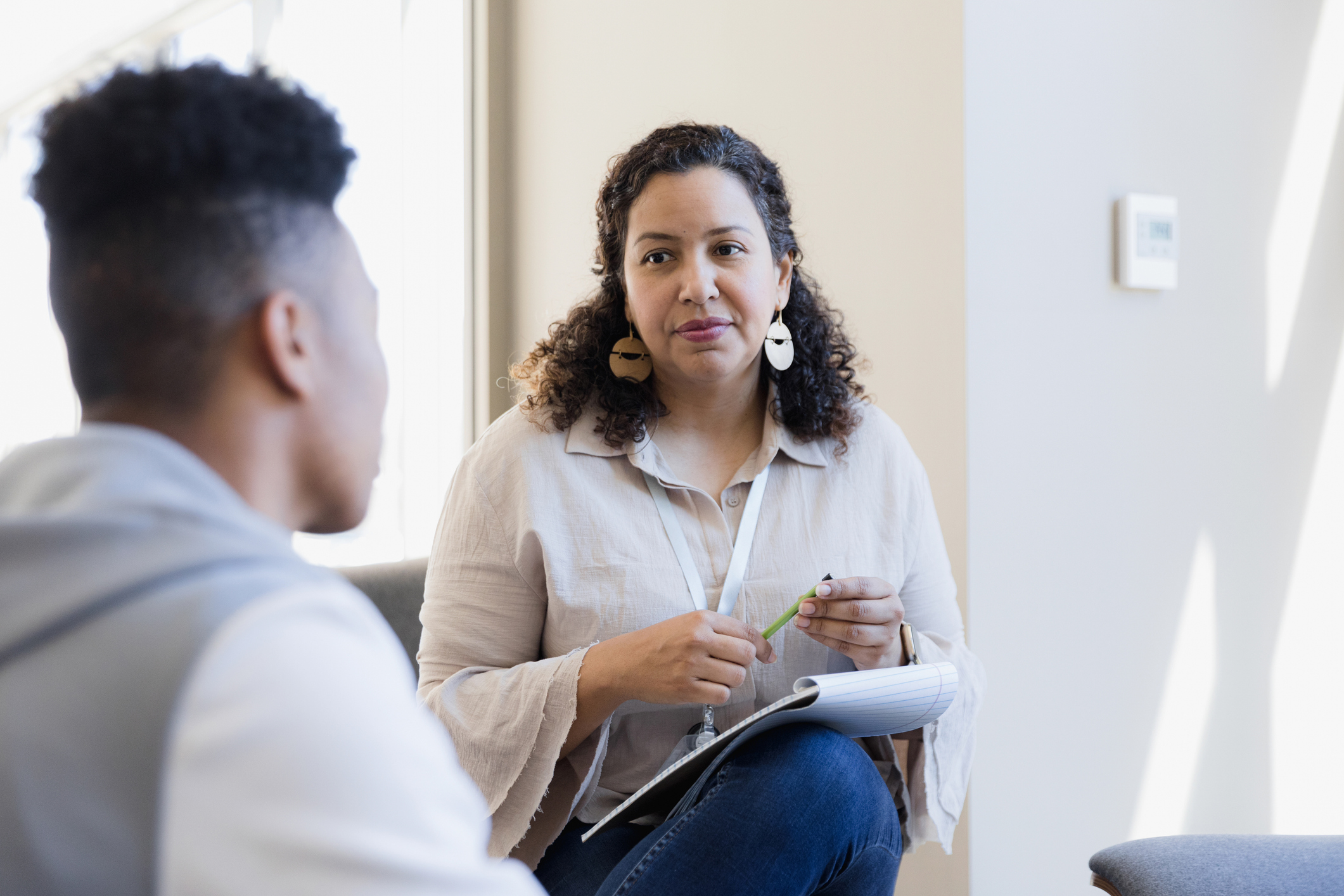 A counsellor listens to a young person in a therapy room.