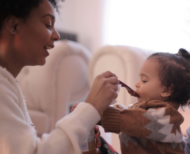 Mother spoon feeding infant.