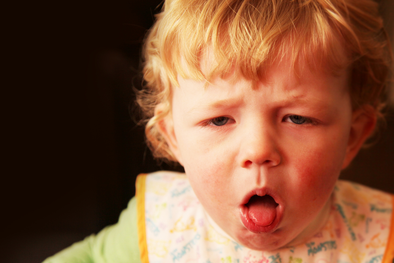 A young boy coughing.