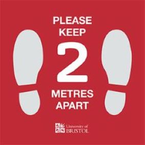 Image of a Floor sticker with a red background asking the user to keep 2 metres distance, showing shoe prints