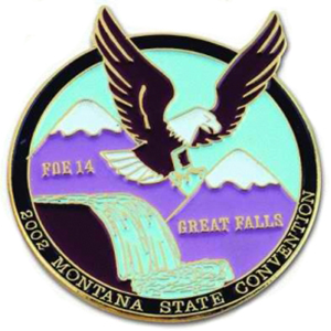 A small colourful circular badge with an image of an eagle and mountains printed onto it