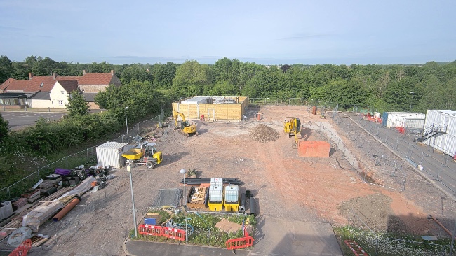An empty building site with a few large yellow construction vehicles