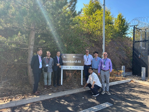 RIKEN and BriCS colleagues standing by the Isambard-AI sign
