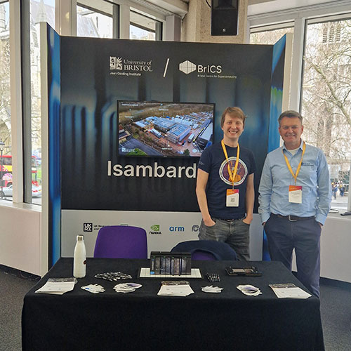 Professor Simon McIntosh-Smith is behind Isambard stand with colleague