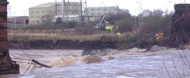 a flooding river with an industrial site in the background