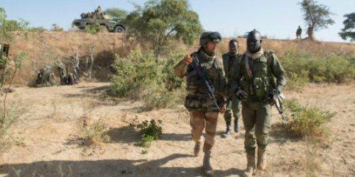 A group of male soldiers walking through an arid landscape.