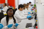 Biology students in lab with gloves, lab coats and safety goggles