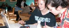 Students sitting at a table working together on a laptop in the School Common Room at 17 Woodland Road. 