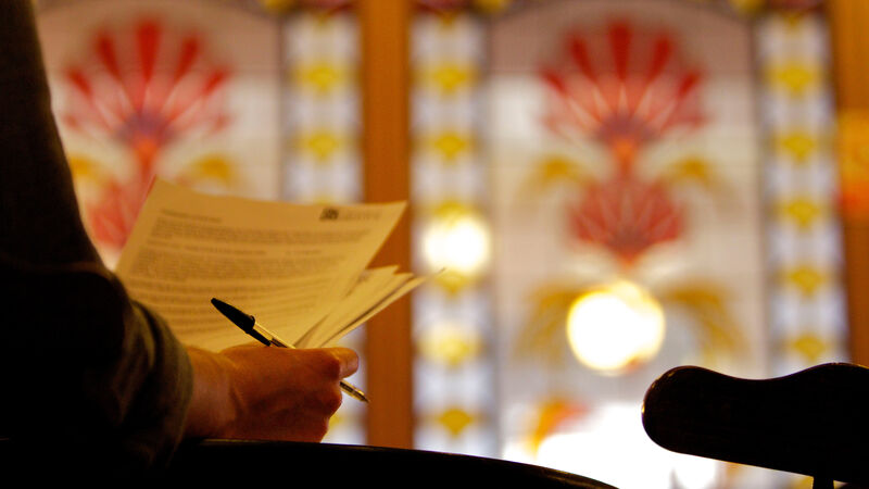 A student holding papers with stained glass windows in the background.