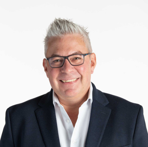 Smiling man with glasses in front of a plain white background