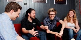 Three men and a woman sitting together talking and smiling.