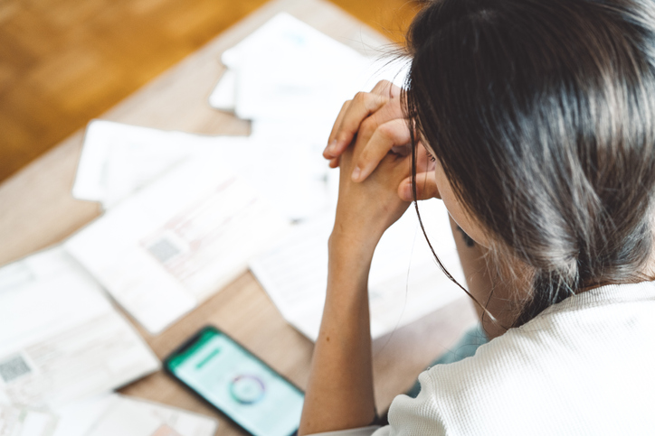 Image shows woman looking at bills/finances
