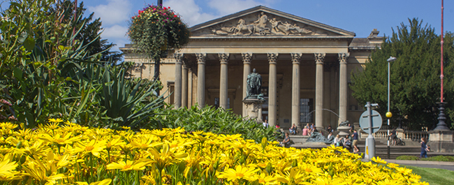 Photograph of the Victoria Rooms with flowers in the foreground.
