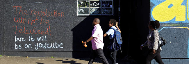 image of pedestrians walking past graffiti on a wall