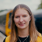 student on a train platform smiling at the camera