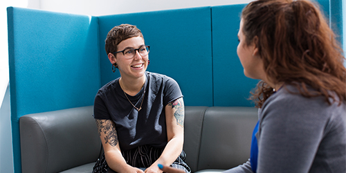 Two students happily chatting in a building on campus