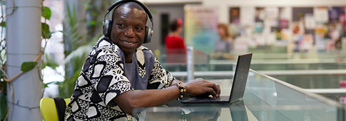 A student smiling while sitting at their laptop in a study space.