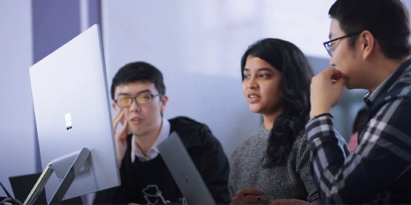 Three students around a computer