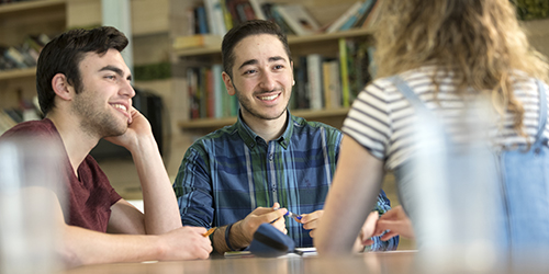 Three students talking around a table.