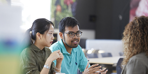 3 students sat at a table having a discussion.