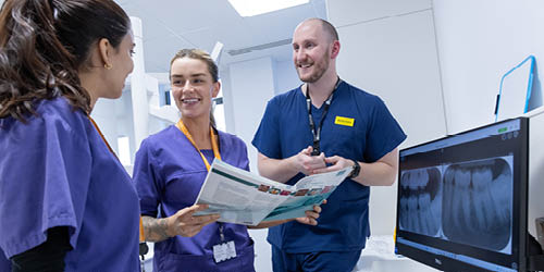 Three dental students looking at an xray