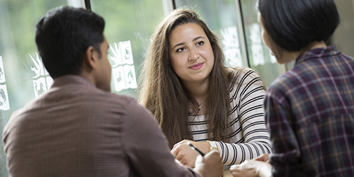 Three students having a discussion at a table in a University of Bristol building.