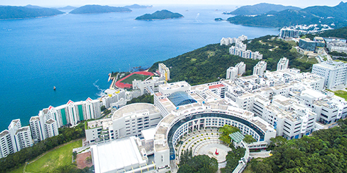 An aerial view of lots of white buildings in a coastal area, with the sea and islands in the distance.