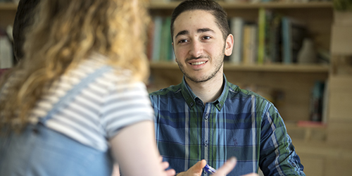 Two people talking in a library.