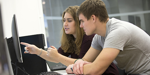 Two people talking and pointing at a computer.