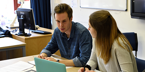 Two people talking in a classroom.