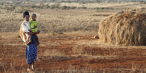 A man holding a child stood in a dry plain