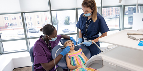 two dental students performing dental work on a young patient