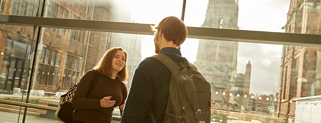 Two students meeting at the Fry Building in the University, with the Wills Memorial Building in the background