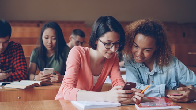 Young people looking at their phones in a lecture hall.